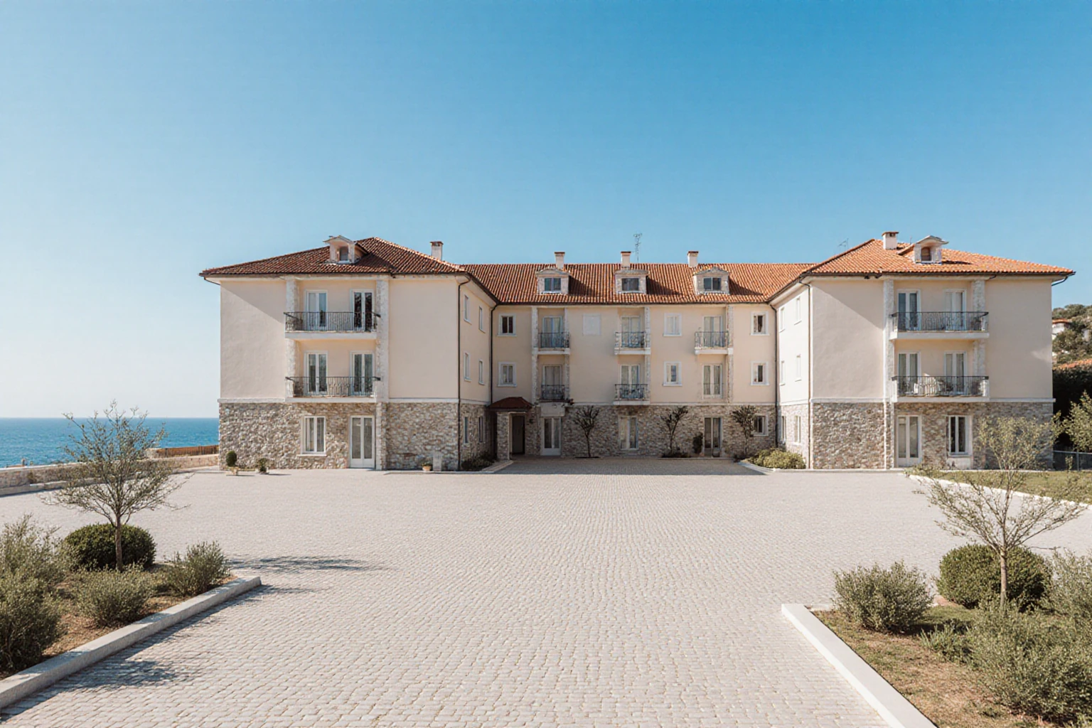 Pale multi-storey buildings with tiled roofs around a coastal courtyard